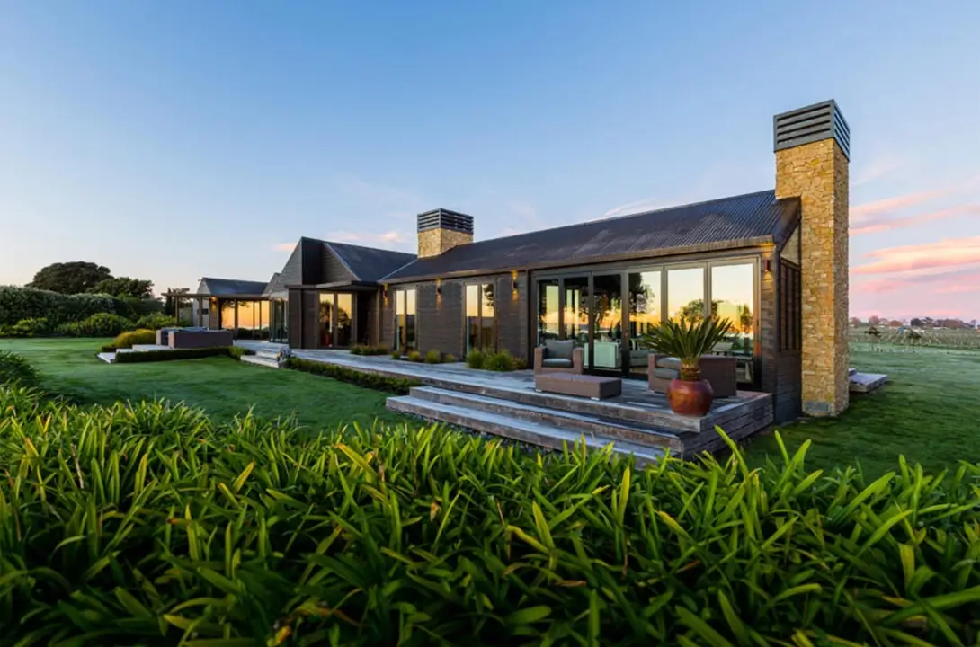 Black wooden country home with a manicured lawn